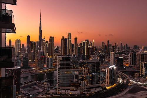 a view of a city skyline at sunset at Simply Comfort Vacation Homes Rental Apartments at Nobles Tower Luxury Burj View in Dubai