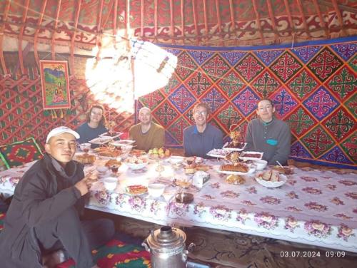 a group of people sitting around a table with food at Yurt camp KEREMET in Kyzart