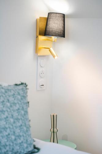 a lamp on a wall with a blue pillow at Chambres hote Le Clos 26 in Bellerive-sur-Allier