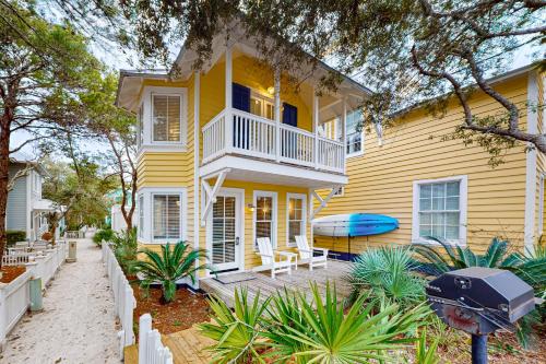 a yellow house with a deck and a surfboard on it at Angel in the Dunes in Seagrove Beach