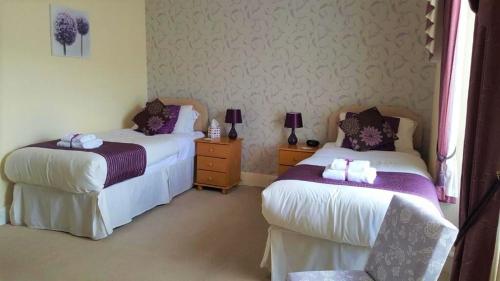 a bedroom with two beds and a chair in it at The Briars - Adults Only in Paignton