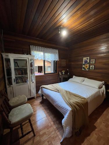 a bedroom with a bed and a chair in a room at Casa da Araucaria nos Alpes de São Francisco in São Francisco de Paula