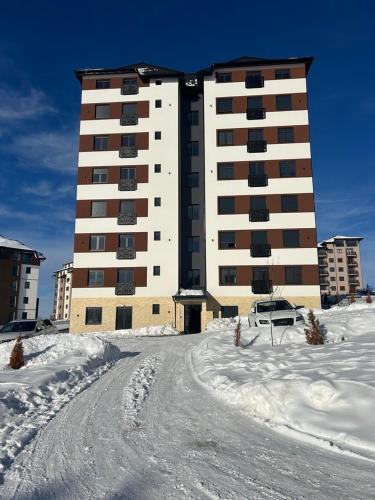 a large building in the snow with a car in front at Apartman 10 in Zlatibor