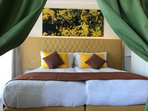 a bedroom with a large bed with yellow and white pillows at Hotel La Campagnola - Green Energy Resort in San Nazzaro