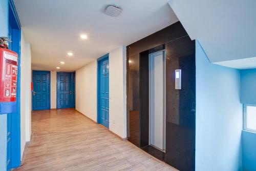 an empty hallway with blue doors and wooden floors at Hotel Aerostar Grand at Yashobhoomi Convention Center in New Delhi