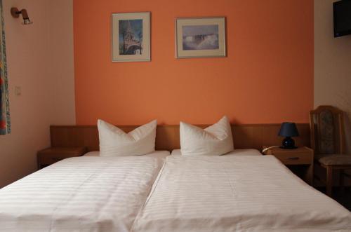 a bedroom with a large white bed with orange walls at Gästehaus Zum Felsenkeller Steigerthal in Nordhausen