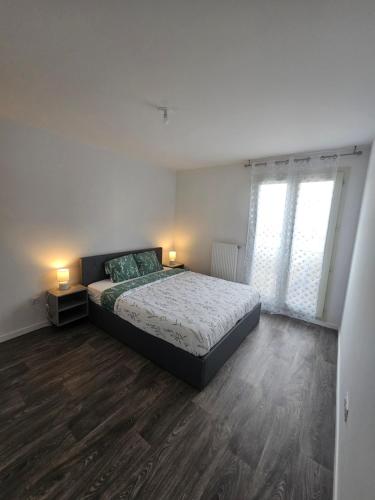 a bedroom with a bed and two lamps on a wooden floor at Le Nid Urbain in Villiers-le-Bel