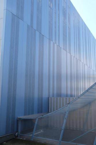 a blue glass building with a staircase next to it at Montagehotel Bed & Steel in Linz
