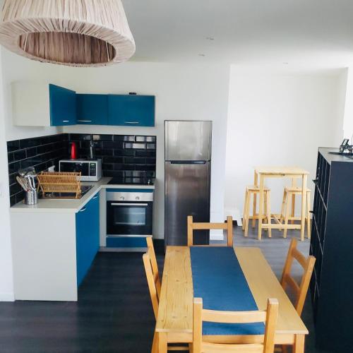 une cuisine avec des placards bleus et une table avec des chaises dans l'établissement Les Halles 1, à La Rochelle