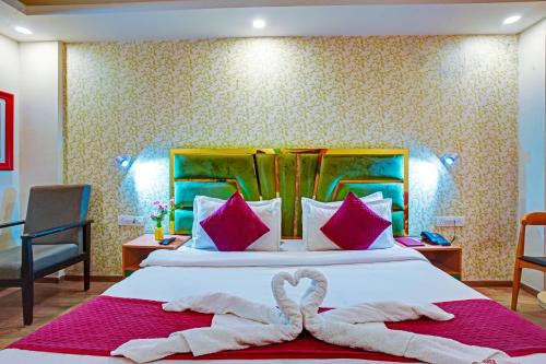 a hotel room with a bed with two swans towels at Hotel Aerostar Grand at Yashobhoomi Convention Center in New Delhi