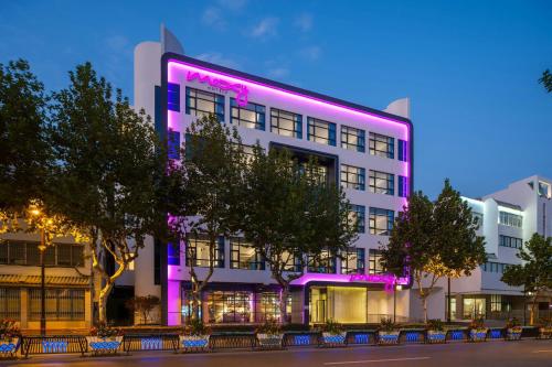 a large white building with a pink sign on it at Moxy Suzhou City Centre in Suzhou