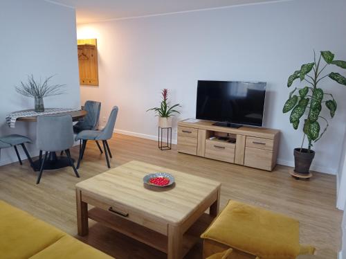 a living room with a flat screen tv and a table at TIMO butas in Druskininkai