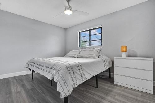 a white bedroom with a bed and a window at Tropical Modern Villa with Pool in Coconut Creek