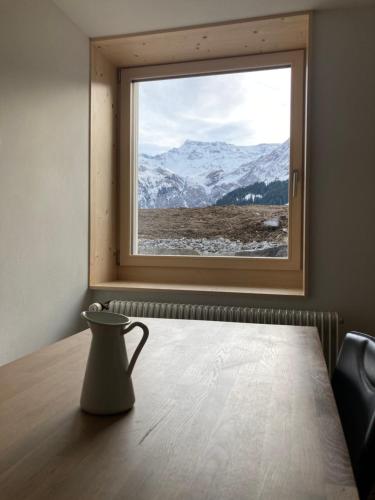 a vase sitting on a table in front of a window at Chalet Wasserfall 3-Zimmerferienwohnung möbliert in Adelboden