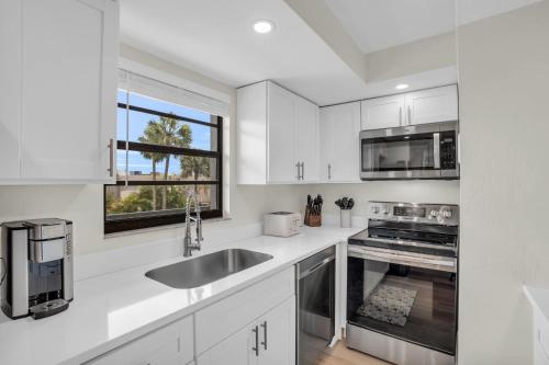 a kitchen with white cabinets and a sink and a window at Updated and Beautiful Views in Naples