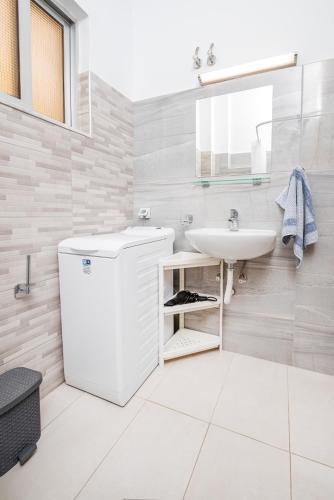 a white bathroom with a sink and a mirror at Silia apartments in Ampavris