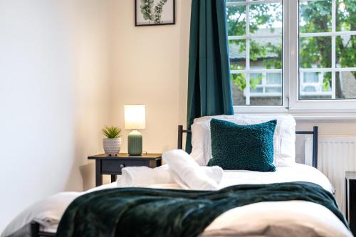 a bedroom with a bed with a blue pillow and a window at Wilkinsons Home-Free parking, Perfect For Contractors & Weekend getaways, Near London City Airport & Excel in London
