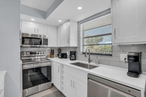 a white kitchen with white cabinets and a sink at Deluxe Condo - Amazing Views in Naples