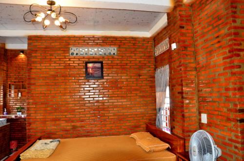 a room with a brick wall with a bed and a fan at BOSA Homestay - Mekong Riverside in Can Tho
