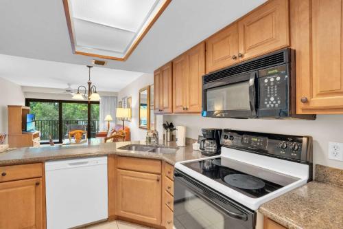 a kitchen with a stove and a microwave at End Unit with Resort Views From Lanai in Naples