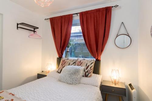 a bedroom with a bed with red curtains and a window at Pleasure beach apartment with garden in Skegness