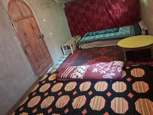 a room with a bed and a table and a door at Camp Sahara inspiration in Mhamid