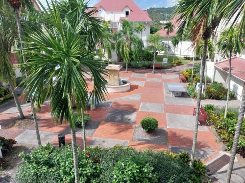 a courtyard with palm trees and a brick walkway at Résidence au cœur des îles Martinique 23 in Bellevue