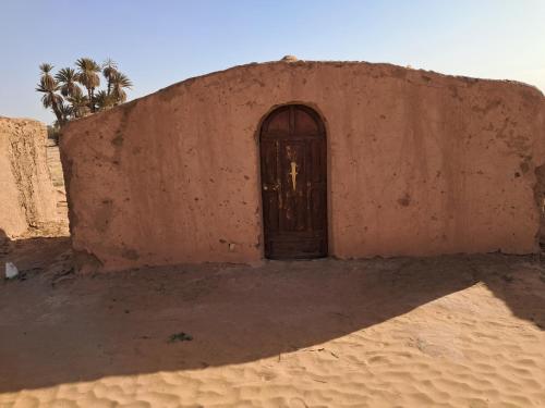a door in the side of a building in the desert at Camp Sahara inspiration in Mhamid