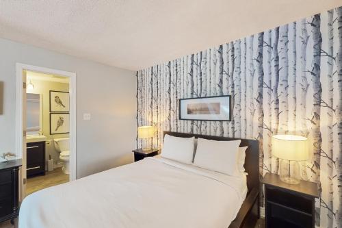 Un dormitorio con una cama blanca y un baño. en Condo 807 at North Creek Resort, en Blue Mountains