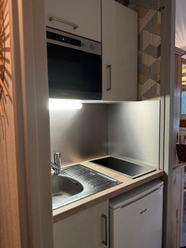 une cuisine avec un évier et un micro-ondes dans l'établissement Le Refuge, à La Bresse