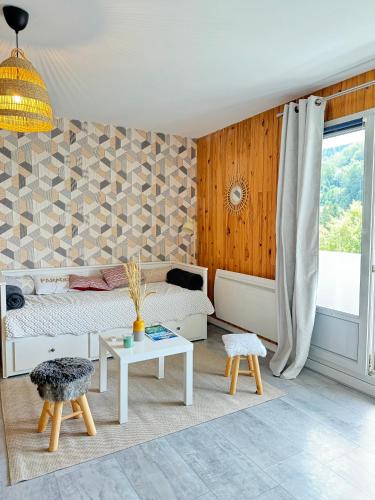 un salon avec un lit et une table dans l'établissement Le Refuge, à La Bresse