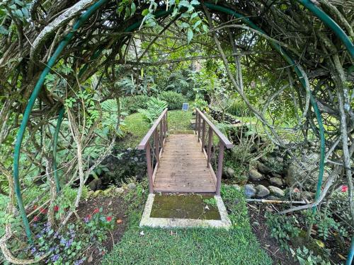a wooden bridge over a path in a garden at Boquete Luxury - Walk to Town in Boquete
