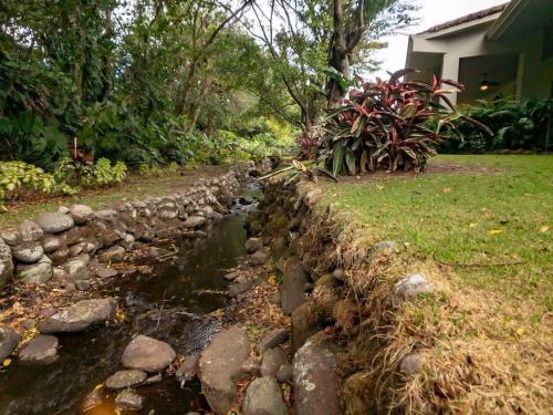 a stone retaining wall next to a stream in a yard at Boquete Luxury - Walk to Town in Boquete