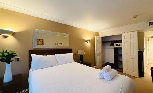 a bedroom with a white bed with towels on it at Hustyns Hotel in Wadebridge