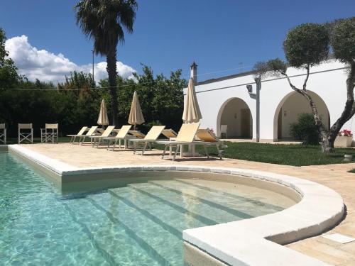 a swimming pool with lounge chairs and umbrellas at Relais Masseria della Colomba - Agriturismo in Francavilla Fontana