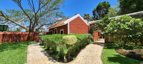 a house with a brick walkway in front of a yard at Hacienda Santa Cruz Merida in Mérida