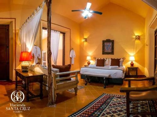 a bedroom with a bed and a chair in a room at Hacienda Santa Cruz Merida in Mérida