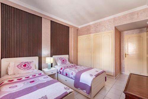a bedroom with two beds and a table in it at Appartement Duplex confort qualité très bien situé in Marrakech