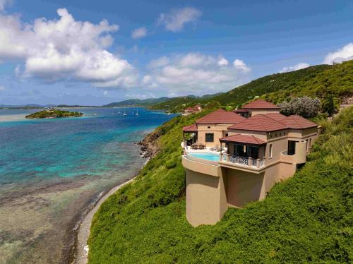 a house on a hill next to the ocean at Scrub Island Resort, Spa & Marina in The Mill