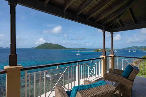 a balcony with two chairs and a view of the ocean at Scrub Island Resort, Spa & Marina in The Mill