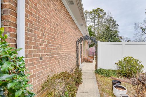 a brick building with a white fence next to a sidewalk at 3 Mi to Dtwn Fayetteville Home with Pool Table in Fayetteville