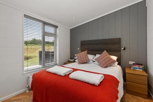 Un dormitorio con una cama grande con una manta roja. en The Duck Pond - Countryside Hot Tub, en Narberth