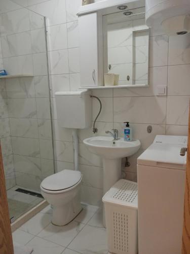 a white bathroom with a toilet and a sink at Apartmani LaVa igalo 1 in Igalo