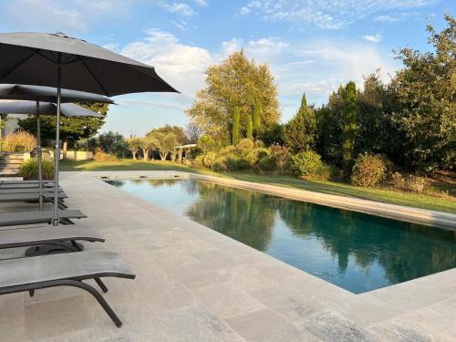 - une piscine bordée de chaises et d'un parasol dans l'établissement EcoLodge romantique proche Lourmarin Piscine Privée Borne recharge, à Puyvert