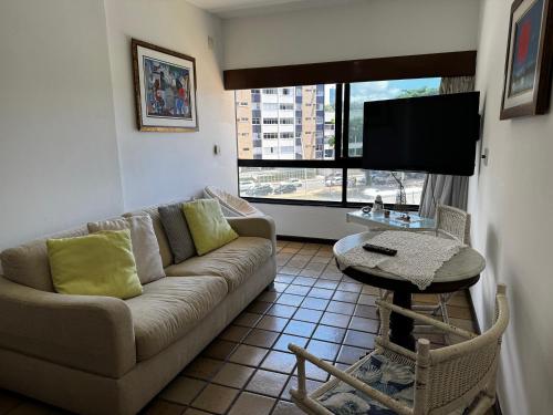 a living room with a couch and a tv and a table at Ondina Apart Hotel Residences in Salvador