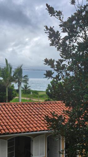 a house with a red roof with the ocean in the background at Pousada Flor de Lótus Caraguá in Caraguatatuba
