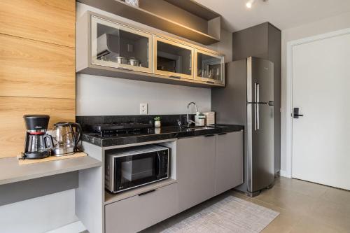 a kitchen with a microwave and a refrigerator at GO 24 by My Way in Porto Alegre