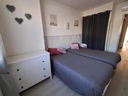 une chambre avec deux lits et une commode dans l'établissement Appartement cosy entièrement climatisé, à Saintes-Maries-de-la-Mer