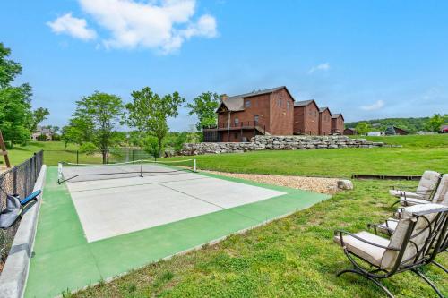 a tennis court with two chairs and a house at Luxury Lakefront Chalet Resort 2 Pools FREE Amenities Dock MiniGolf Waterslide in Lampe