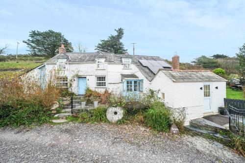 an old white house with a fence in front of it at Shilla Mill - Just off the Beach in Polzeath